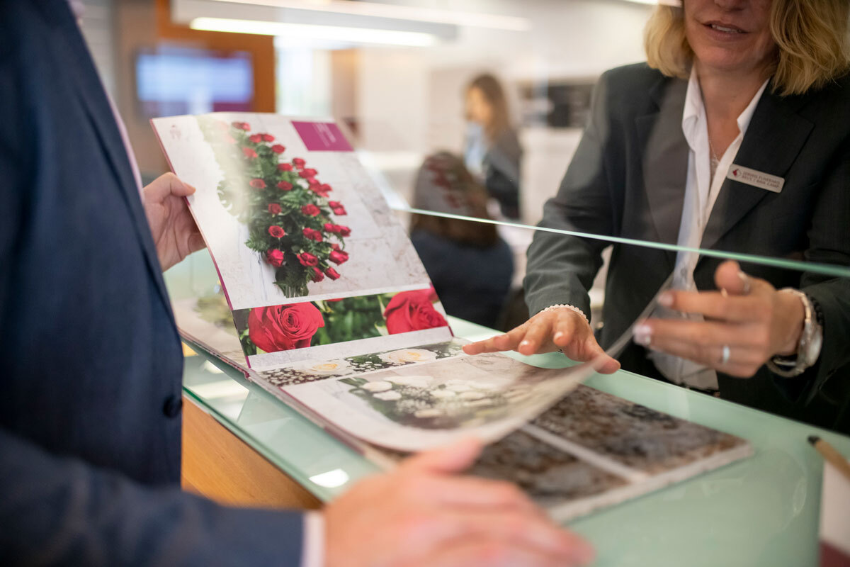 Una treballadora dels serveis funeraris ensenya el catàleg de detalls florals.